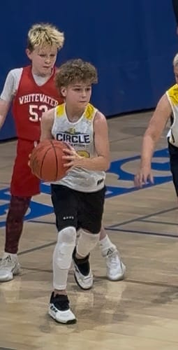 Customer's grandson wearing the Youth Performance Shorts while holding a basketball on a court.