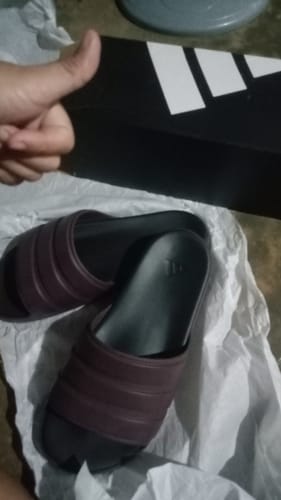 A reviewer gives a thumbs-up next to a pair of new Aurora Ruby adidas Znsory Unisex Slides resting on packing paper.