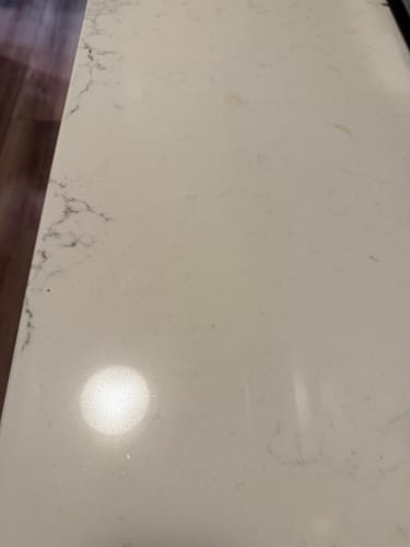 Close-up of a customer's shiny white stone countertop, showing the cleaning results of the Trial Pack.