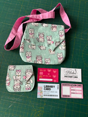 Customer's handmade bag and pouch made from Kitty Squad Cotton Poplin Fabric, shown with toy cards on a cutting mat.