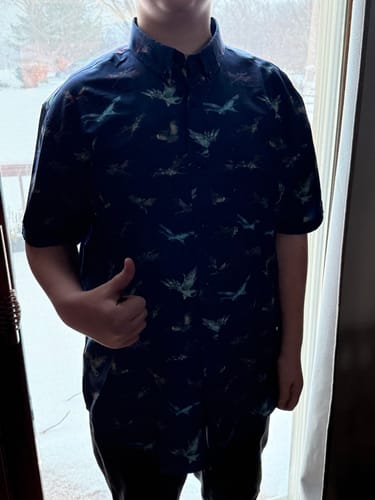 Customer wearing the dark Avatar Soaring Banshees short-sleeve shirt and giving a thumbs-up.