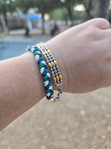 Close-up of a customer's wrist wearing the colorful woven DAVID Bracelet outdoors.