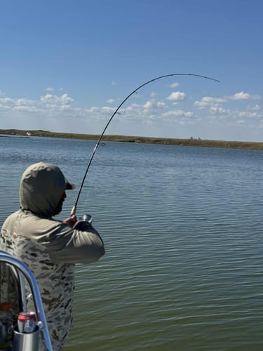 Reviewer on a boat using the Waterloo Outlaw rod, which is bent in a deep arc while fighting a fish.