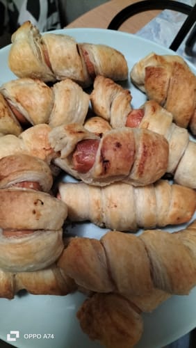 Clientul arată o farfurie plină cu crenvurști în foietaj aurii, gătiți cu Air Fryer Novio StonePro.