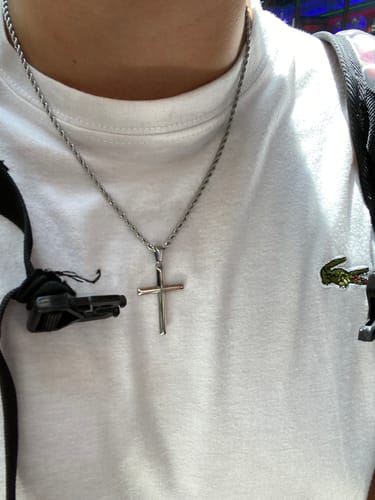 Cliente usando el colgante Crucifijo con su cadena sobre una camiseta blanca.