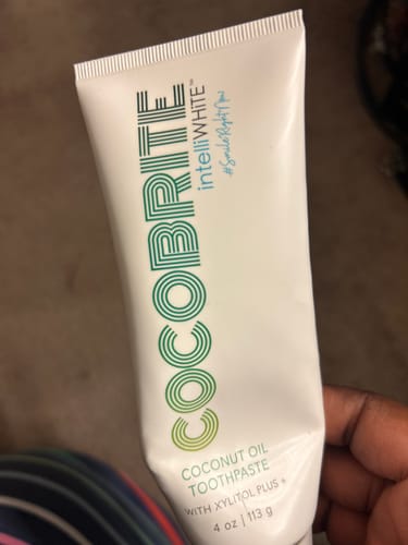 Customer holding a white tube of Cocobrite Coconut Oil Toothpaste.