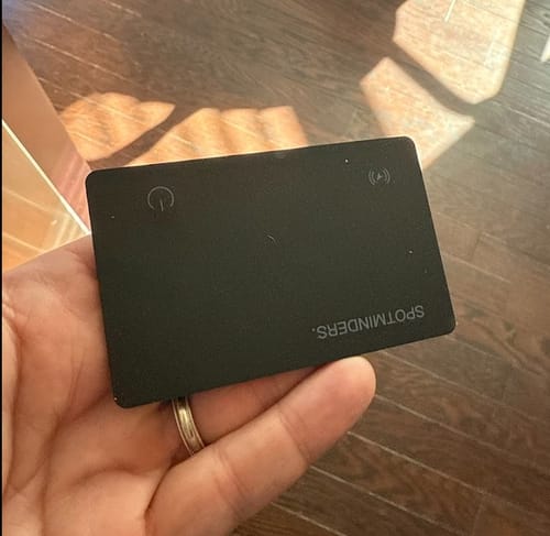 Customer holding the slim, black Spotminders Tracking Card in their hand.