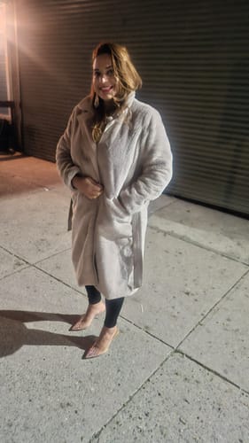 Customer wearing the cozy, taupe Cataleya Long Faux Fur Coat outdoors at night.