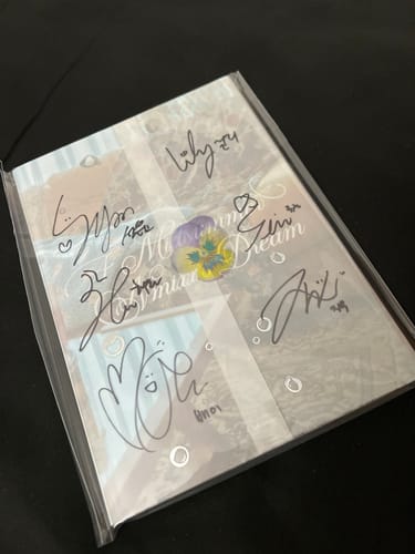 Customer's hand-signed NMIXX "A Midsummer NMIXX’s Dream" promo album shown inside a clear sleeve.