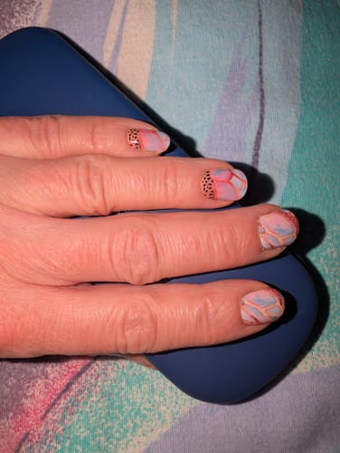 Nahaufnahme der Hand einer Kundin mit den Wild Candy Marble Nagelfolien, die ein Marmor- und Leopardenmuster zeigen.