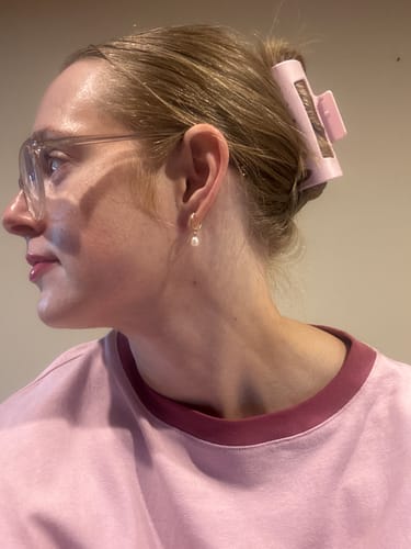 A reviewer from the side, wearing a pink cloud clip to hold their blonde hair up in a bun.