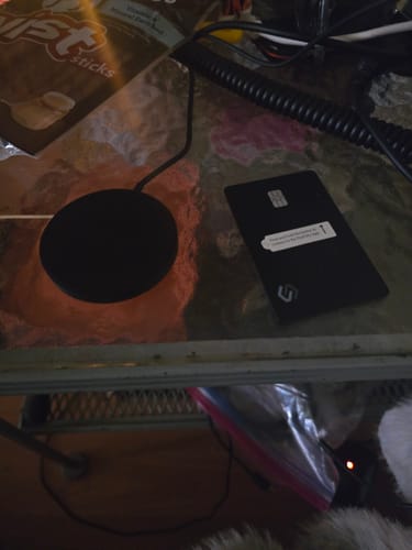 Customer's black SPOTMINDERS Tracking Card PRO on a table next to the recommended wireless charger.