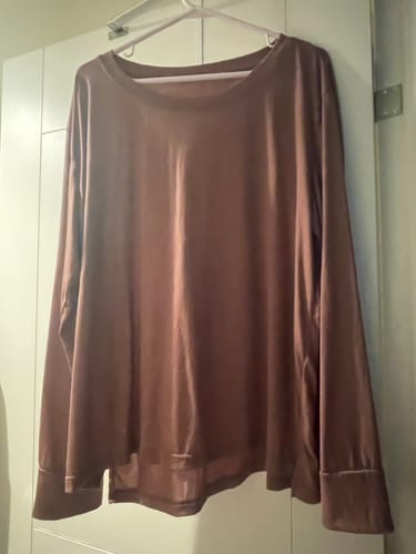 Customer's long-sleeve Ashlie Lounge Top in nutmeg hanging on a closet door.