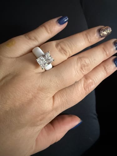 Reviewer's hand wearing the white Silicone Ring with a large, emerald-cut stone against dark clothing.