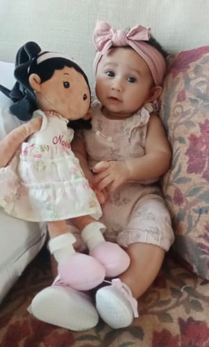 Customer's Personalized Princess Petal doll with black curly hair and a floral dress, sitting next to a baby on a couch.