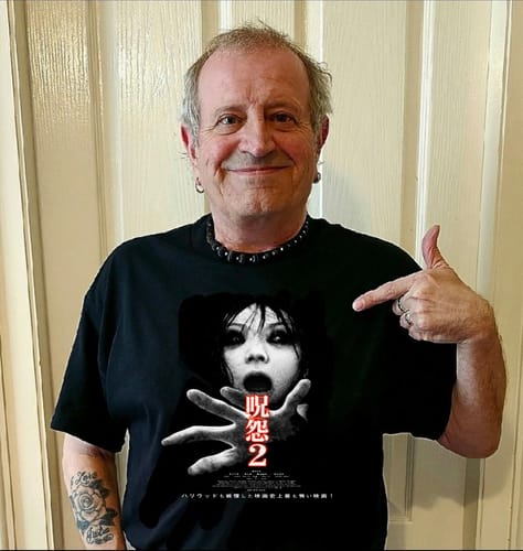 Reviewer smiling and pointing to the 'Ju-on 2' graphic on their black unisex t-shirt.