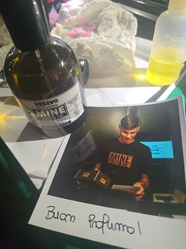 Il profumo VESEVO del recensore su un tavolo, con una foto e un biglietto scritto a mano 'Buon Profumo!'.