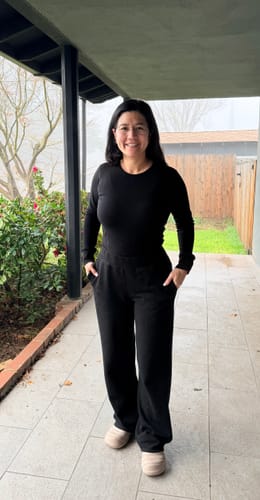 Reviewer standing on a patio wearing the black Hannah Long Sleeve Top, showing its athletic fit.