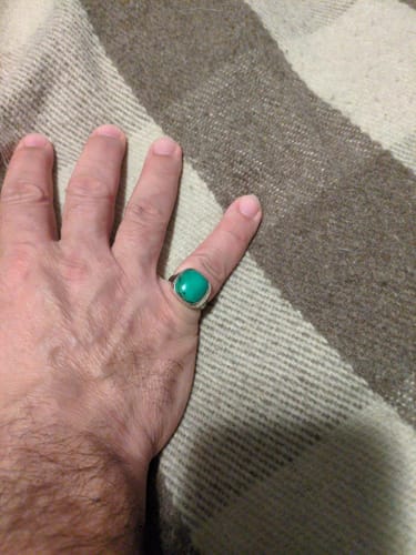 Customer wearing the square turquoise signet ring on their index finger against a striped blanket.