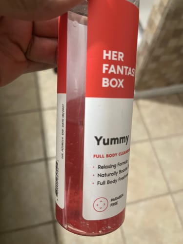 Reviewer holding a bottle of Yummy Shower Gel, showing the red and white label.