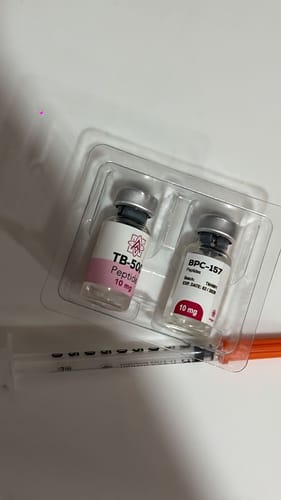 Cliente muestra los viales BPC-157 y TB-500 en su empaque plástico, con una jeringa al lado.