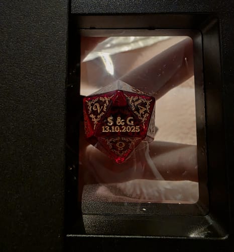 Customer holding a personalized red D20 dice with gold lettering inside its black presentation box.