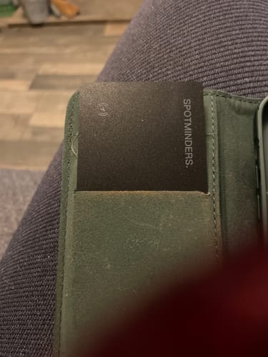 Customer's SPOTMINDERS Tracking Card partially inserted into a green wallet.