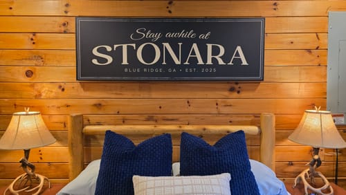 Customer's personalized black farmhouse sign hanging on a wood wall above a bed.