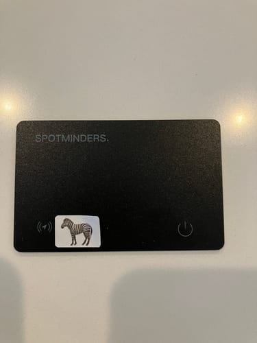 Customer's black SPOTMINDERS Tracking Card on a surface with a small zebra sticker.