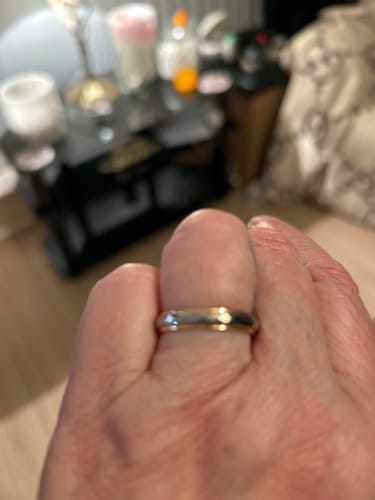 Close-up of a customer's hand wearing the two-tone Liora ring, showing its fit and finish indoors.