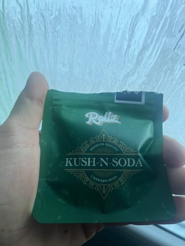 Customer holding the green, sealed packaging for KUSH n Soda THCA Flower.