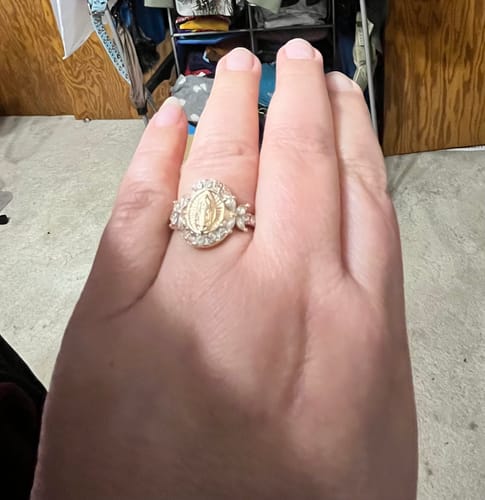 A customer's hand wearing the gold-colored Elegant Virgin Mary Emblem Ring.