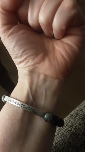 A close-up of a customer's wrist wearing the 'GOD IS IN CONTROL' engraved beaded bracelet.