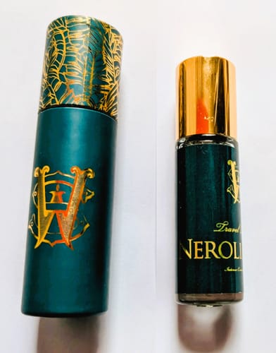 Reviewer's travel-size Neroliander perfume bottle shown next to its decorative teal and gold case.