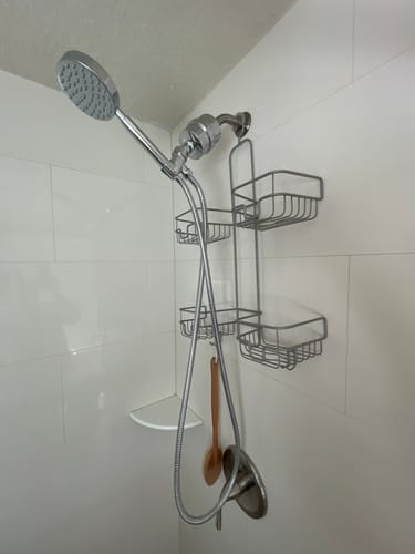 Customer's sleek handheld shower head with filter installed in a white tiled shower.