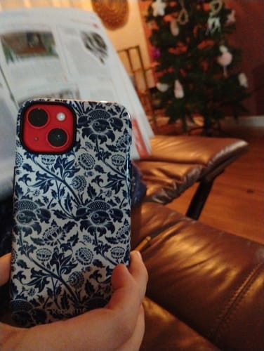 Customer holding a phone displaying the blue and white floral Shivery case.
