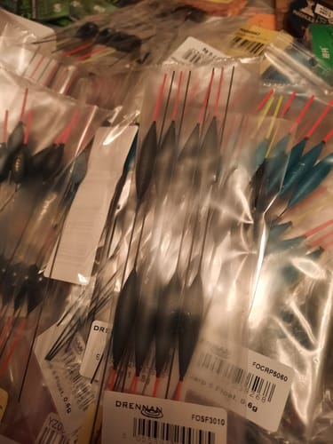 Een recensent toont een grote hoeveelheid SF1 Pole Float-dobbers in hun doorzichtige verpakking.