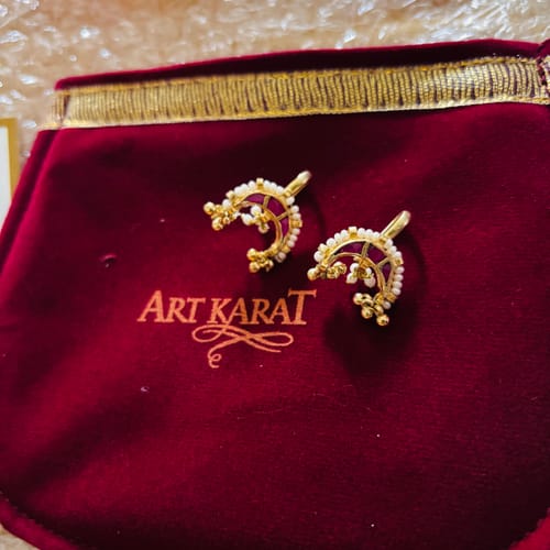 Customer's Shruti gold plated earcuffs with pearls and red stones on a branded red velvet pouch.