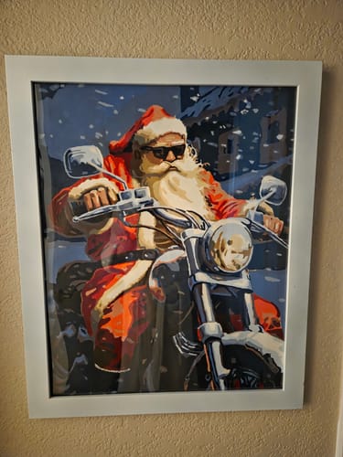 Customer's finished Rush Hour paint-by-number, showing Santa on a motorcycle, in a white frame on a wall.