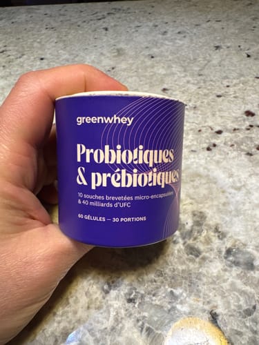 Client tenant le pot en carton violet des Probiotiques & Prébiotiques dans sa main.