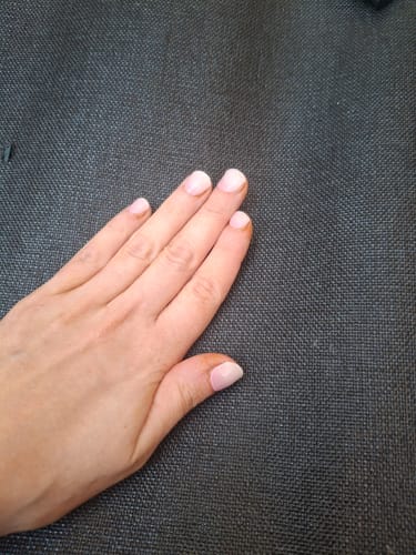 Eine Kundin zeigt ihre Hand mit den 'Babyboomer Pink' UV Gel Nagelfolien, die leicht herausgewachsen sind.
