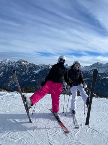 Reviewer posing on a snowy mountain in bright pink, baggy Rose Snow Pants.