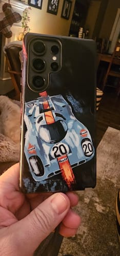 Customer holding their custom Galaxy S25 Ultra case featuring a detailed graphic of a light blue and orange race car.
