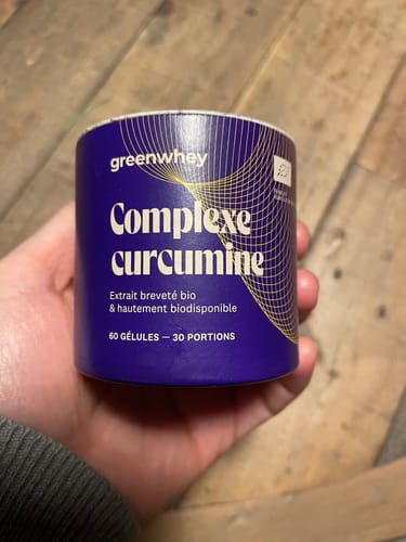 Client tenant dans sa main le pot bleu du produit Complexe curcumine.