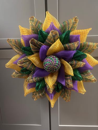 Customer's flower-shaped wreath made with purple, green, and gold vertical ombre mesh.