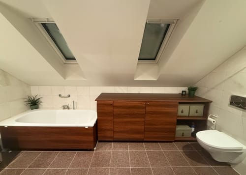 Kunde viser Warm walnut kontaktplast brukt på baderomsmøbler og et badekar i et loftsbaderom.