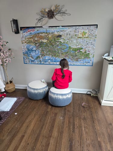 A customer's child sits looking at a large wall map, the subject for their Magnifier Glass.