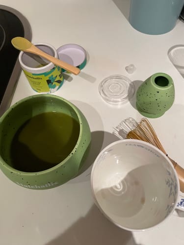 Cliente mostrando su Pack Cerámica verde moteado, con el bol lleno de matcha y un batidor al lado.
