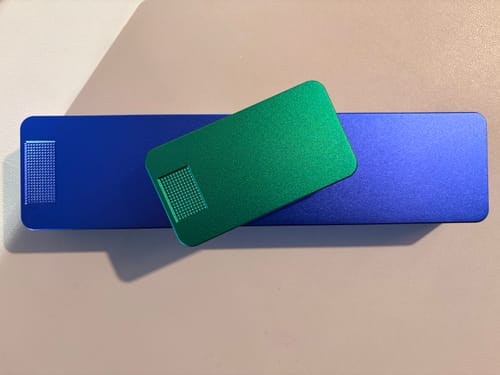Customer's two metal pill cases, a large blue one and a smaller green one, on a neutral surface.