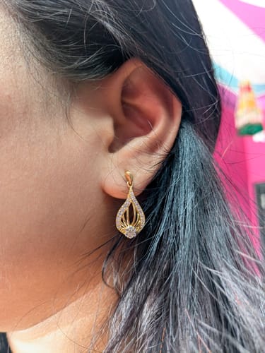 Customer wearing the gold Golden Glint Earring. A close-up shows the sparkling tear-drop design.